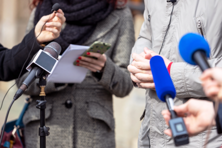 Media with microphones interviewing someone